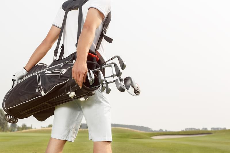 Golfer carrying his golf bag across a golf course