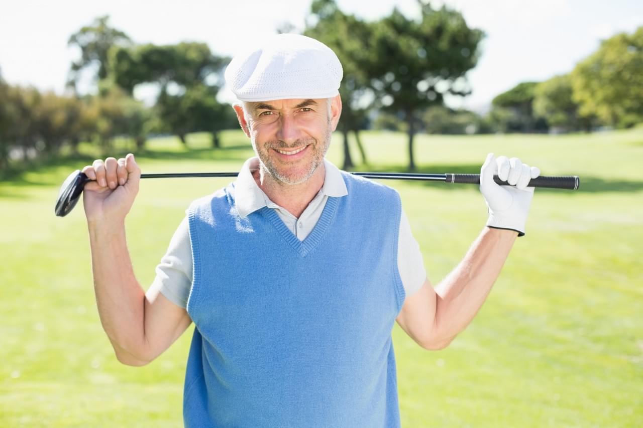 Cheerful golfer smiling at camera on a sunny day at the golf cou